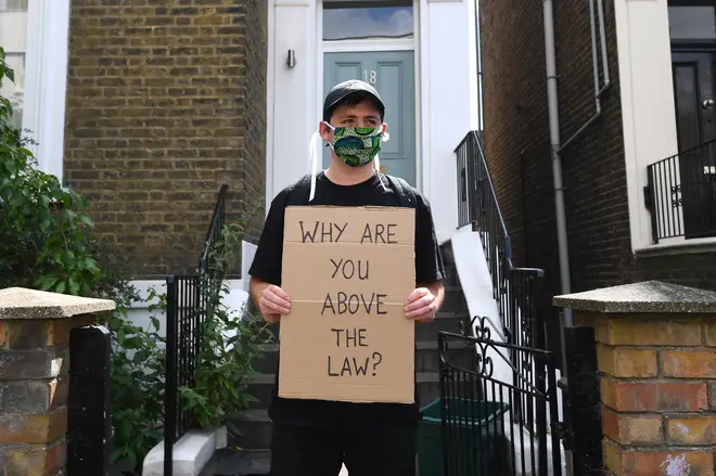 An activist stands outside Dominic Cummings' house in protest