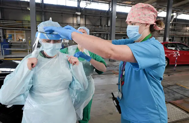 Medical staff put on their personal protective equipment (PPE) at an MOT testing centre in Belfast