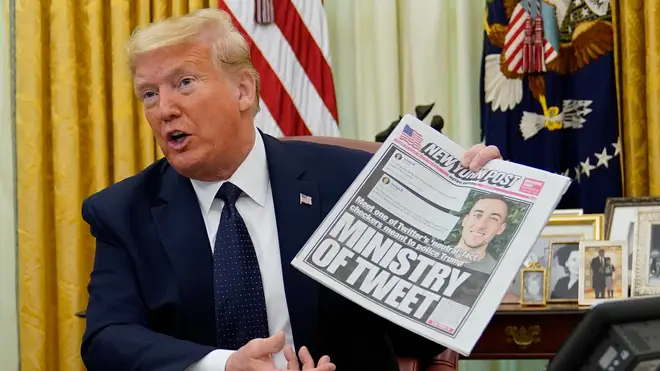 President Donald Trump holds up a copy of the New York Post as speaks before signing an executive order