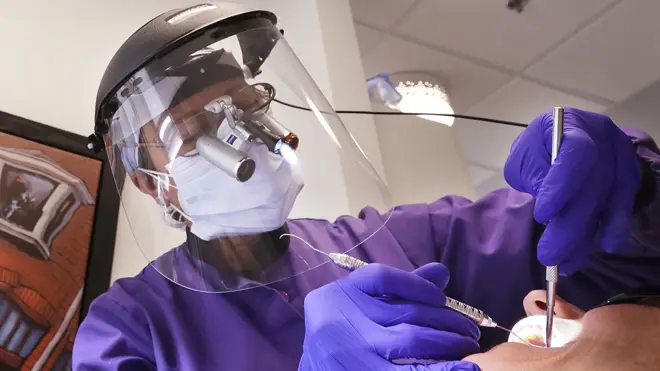 A dentist wears additional protective equipment