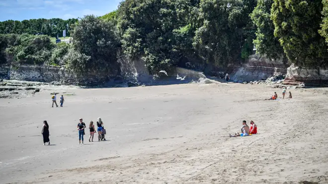 People exercise and rest on the beach in hot weather in Barry Island, Wales