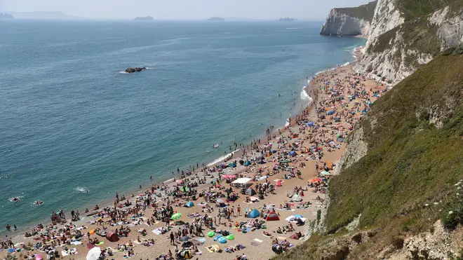 People enjoying the good weather on the beach at Durdle Door, near Lulworth in Dorset