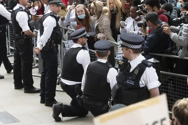 Two officers kneel down in front of protesters at Downing Street