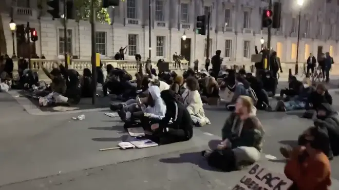 A small group of protesters sat in central London into the evening, singing: "Where is the Love"