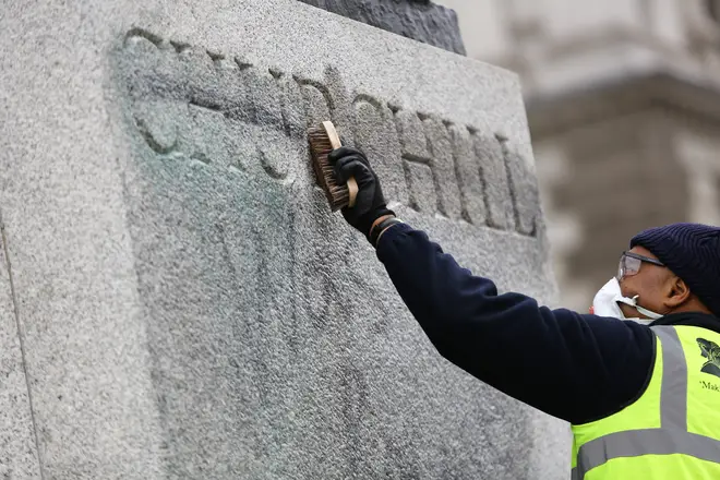 Volunteers clean graffiti which was sprayed on a statue for Winston Churchill