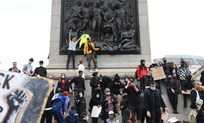 Protestors stood on a monument holding placards