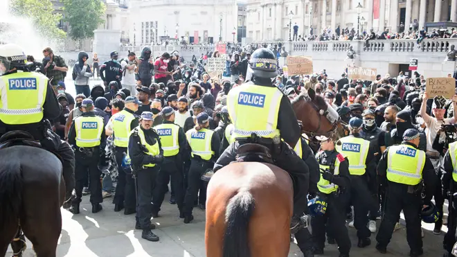 A line of riot police and protesters in London today