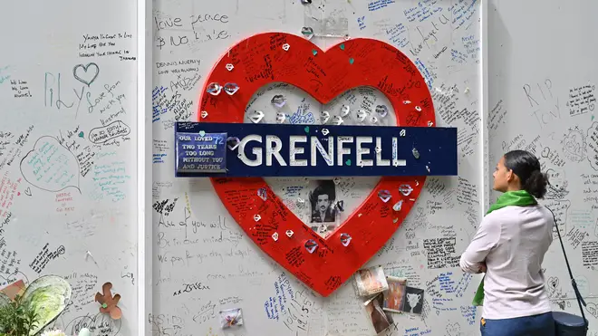 A woman reads messages of support written on the wall surrounding Grenfell tower