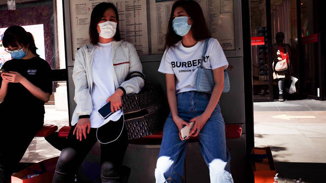 Two women pictured shopping in face masks in London as it was announced the covid-19 threat level is being reduced