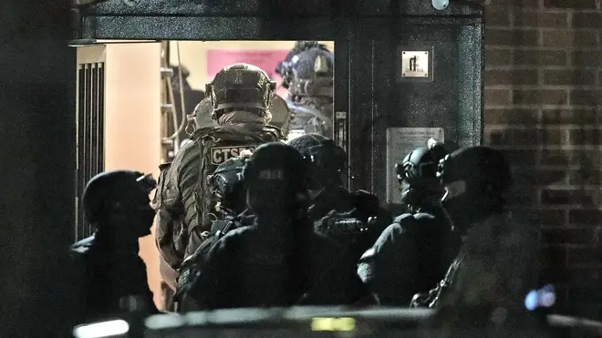 Counter terrorism officers are seen at a nearby address