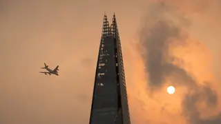 A plane flies past the Shard as the sky takes on an unusual orange hue