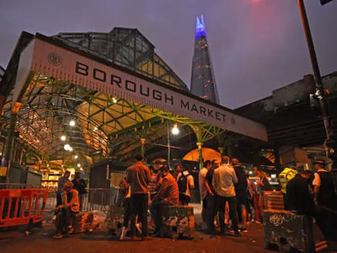 The Shard is lit blue in honour of the NHS as people are out in Borough Market, London