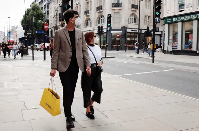 Shoppers carry a bag of shopping from department store Selfridges along Oxford Street