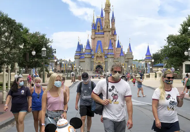 Guests wear masks as required to attend the official reopening day of the Magic Kingdom at Walt Disney World