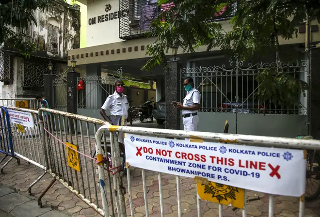 Policemen stand guard outside a residential complex where some residents tested COVID-19 positive in Kolkata, India