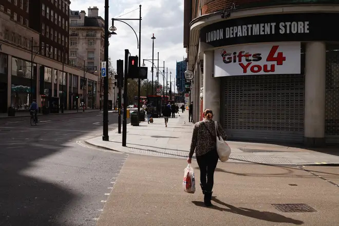A woman carries a bag of food shopping past shuttered stores on a near-deserted Oxford Street