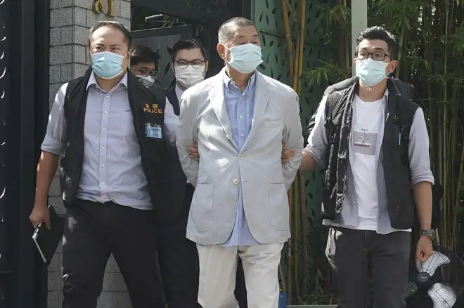 Hong Kong media tycoon Jimmy Lai, center, who founded local newspaper Apple Daily, is arrested by police officers at his home in Hong Kong