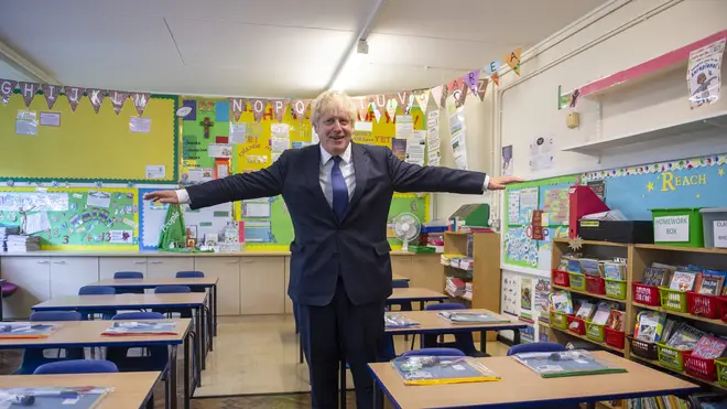 Prime Minister Boris Johnson holds his arms out like an aeroplane, demonstrating the two metre distancing rule, during his visit to St Joseph's Catholic Primary School in Upminster, east London