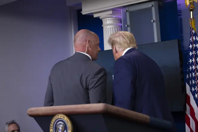 United States President Donald J. Trump is removed from the White House Briefing Room by a US Secret Service agent