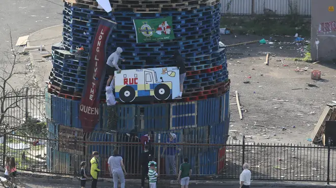 Pictures and flags are added to a bonfire in the Bogside area of Derry City