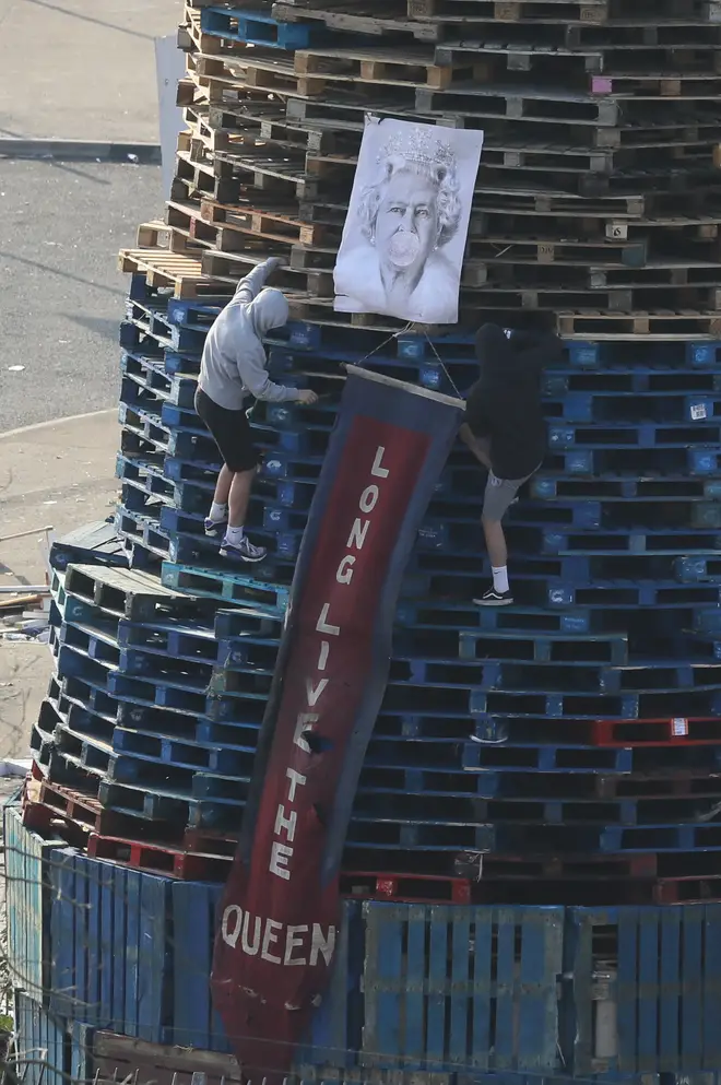 An image of Queen Elizabeth II is added to a bonfire in the Bogside area of Derry City
