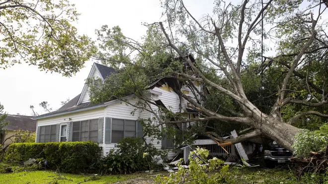 A tree rests on a house on West Orange Avenue in Orange, Texas the morning after Hurricane Laura made landfall