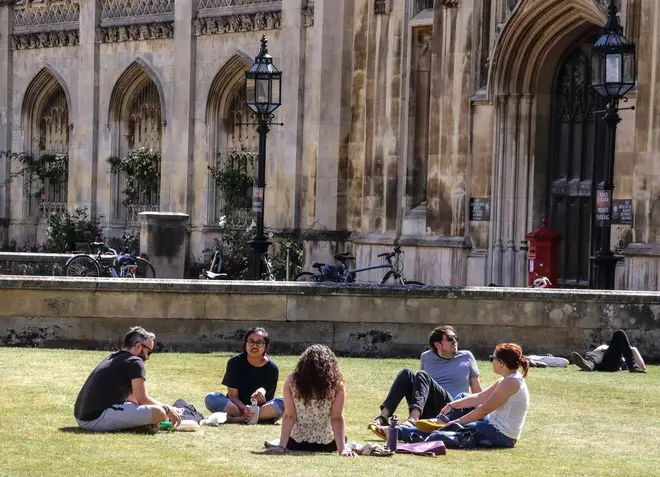 File photo: People sit on the grass outside the main entrance to Kings College, part of Cambridge University