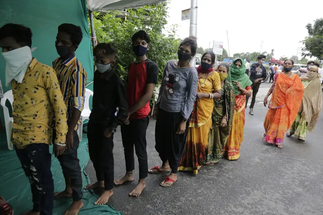 People stand in a queue to test for COVID-19 at a check post erected to screen people coming from outside the city, in Ahmedabad, India
