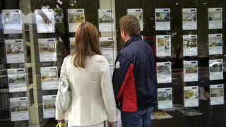 A couple look in an estate agent's window