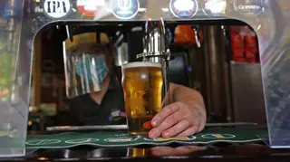 A barman in PPE place a pint on the bar