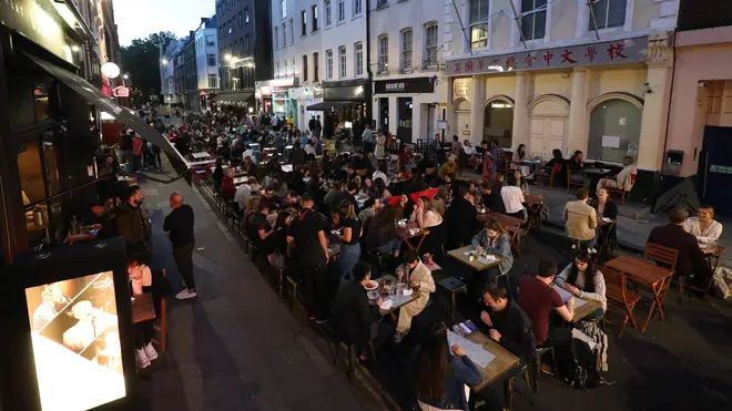 People eating on restaurant tables placed outside on Frith St in Soho, London
