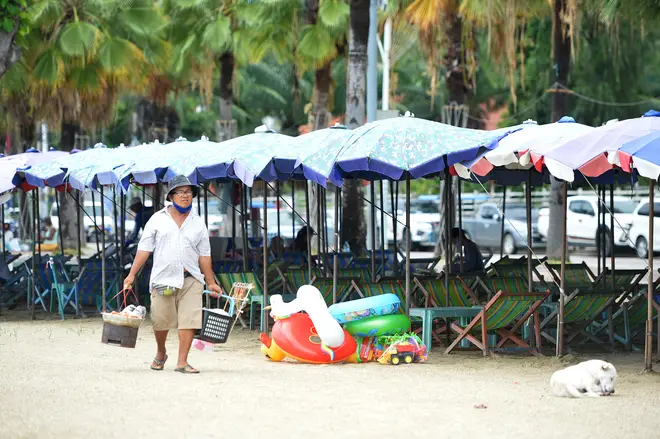A vender carries food for sale at Pattaya beach in Chonburi province, Thailand