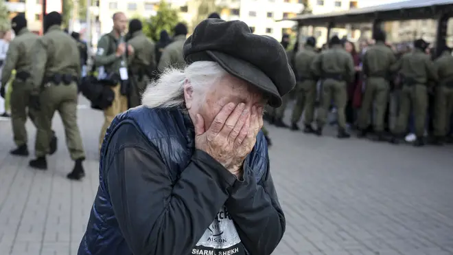 An elderly woman reacts as police officers detain women during an opposition rally in Minsk, Belarus