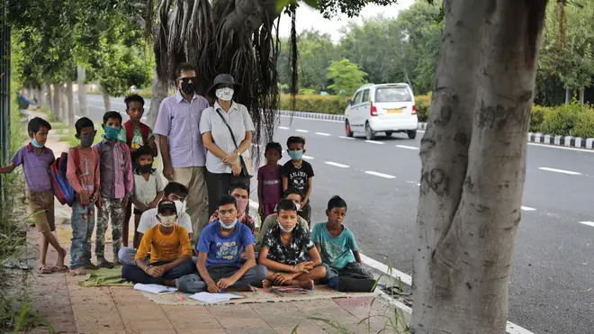Former diplomat Virendra Gupta and his singer wife Veena Gupta with children who they teach on a pavement in New Delhi, India