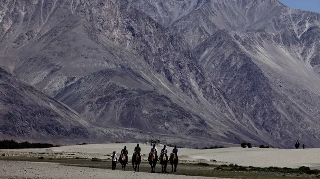 Tourists ride camels at Nubra valley, in the disputed region of Ladakh, India (Channi Anand/AP)