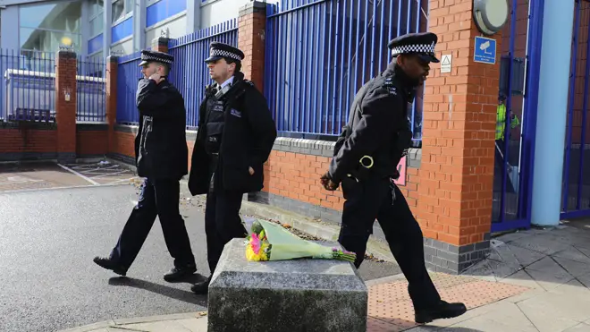 Police walk past flowers left in tribute to the fallen officer