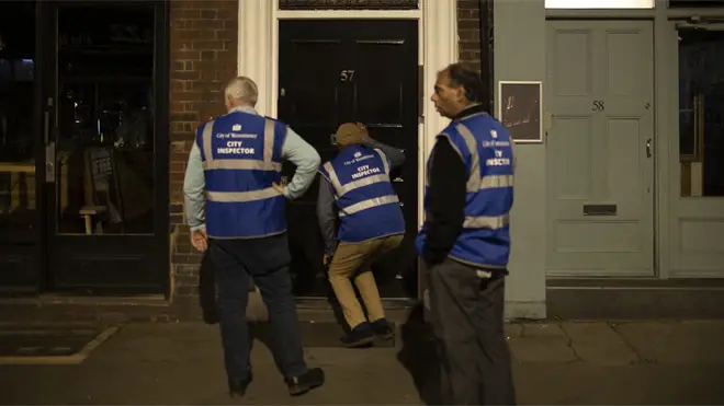 City inspectors look through the letterbox of a cocktail club