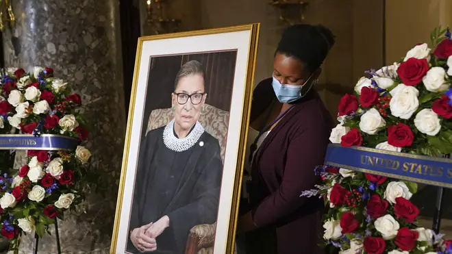 A staff member places a photo of Justice Ruth Bader Ginsburg before a ceremony for her to lie in state in Statuary Hall at the US Capitol