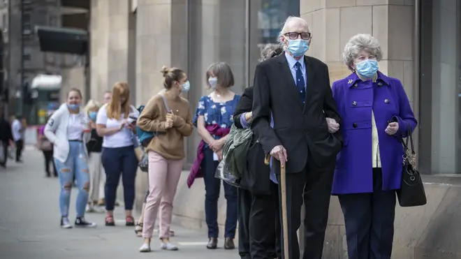 Shoppers queue while wearing face masks