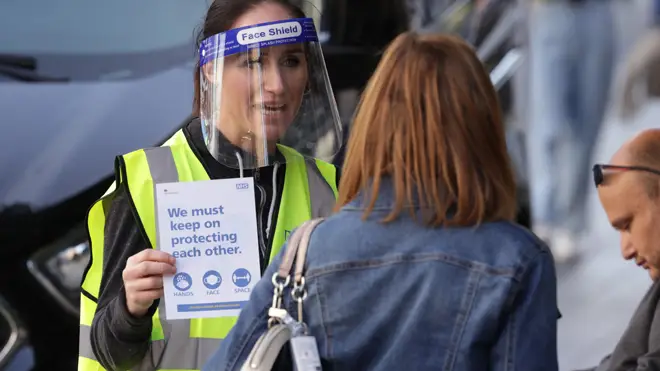 A woman handing out leaflets promoting the new NHS Covid-19 app in Liverpool