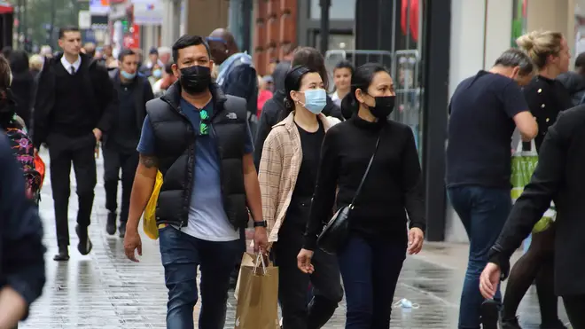 People walk along Oxford Street while while wearing face masks