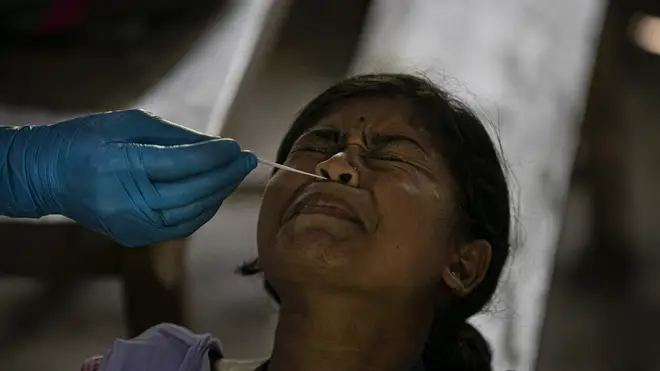 An Indian health worker takes a nasal swab sample from a student to test for coronavirus