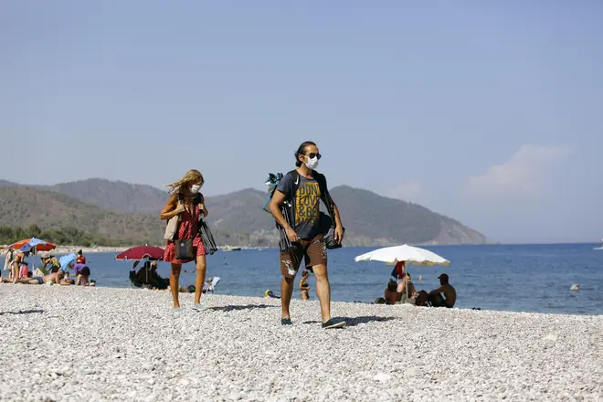 People wearing face masks walk on a beach in Antalya, Turkey