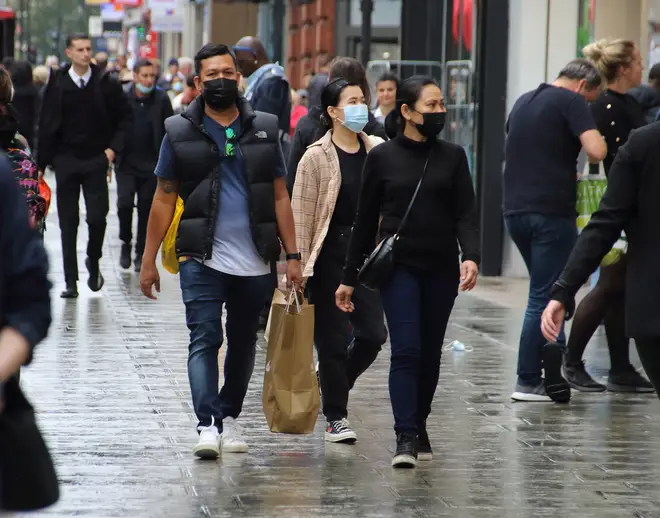 People walk along Oxford Street while while wearing face masks