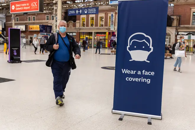 File photo: Passengers in protective face masks are seen walking on a sideway at Victoria Station
