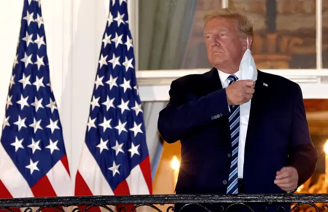 President Donald Trump removes his mask upon return to the White House