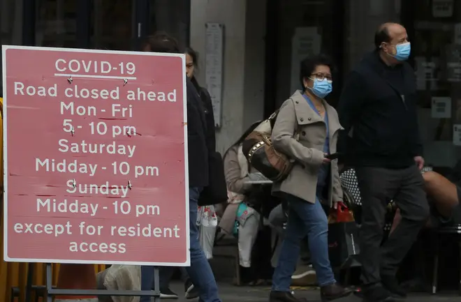 People walk past a sign that refers to COVID-19 closures in London