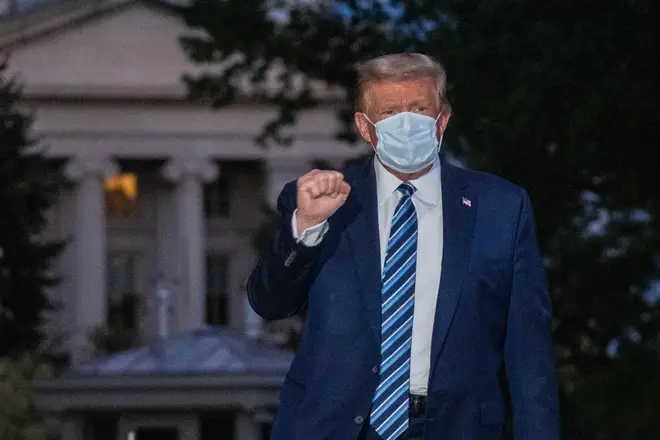 President Donald Trump poses for the cameras as he returns to the White House in a mask after his stay in hospital for coronavirus