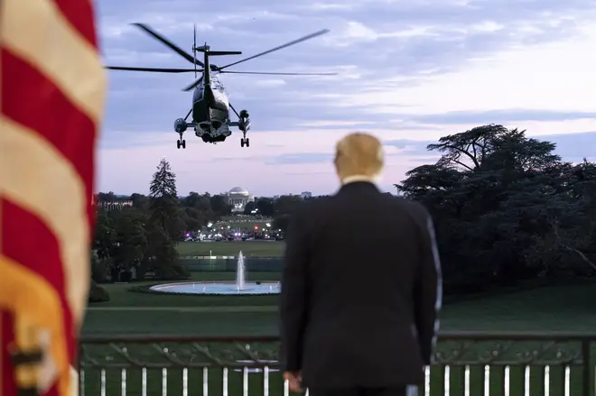 President Trump salutes Marine One from the Blue Room Balcony of the White House after returning from Walter Reed National Military Medical Center
