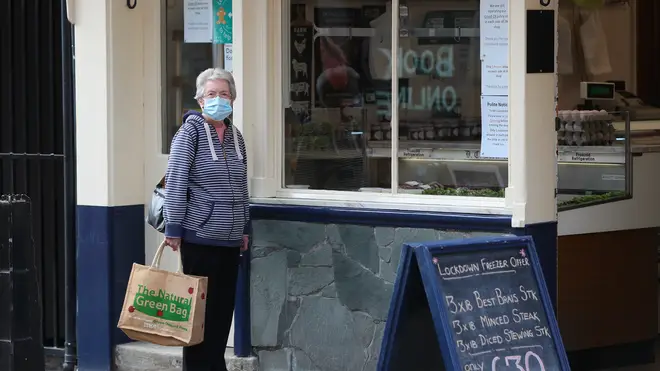 A woman waits outside a butchers in Ormskirk, Lancashire, that is offering a ‘lockdown freezer offer'